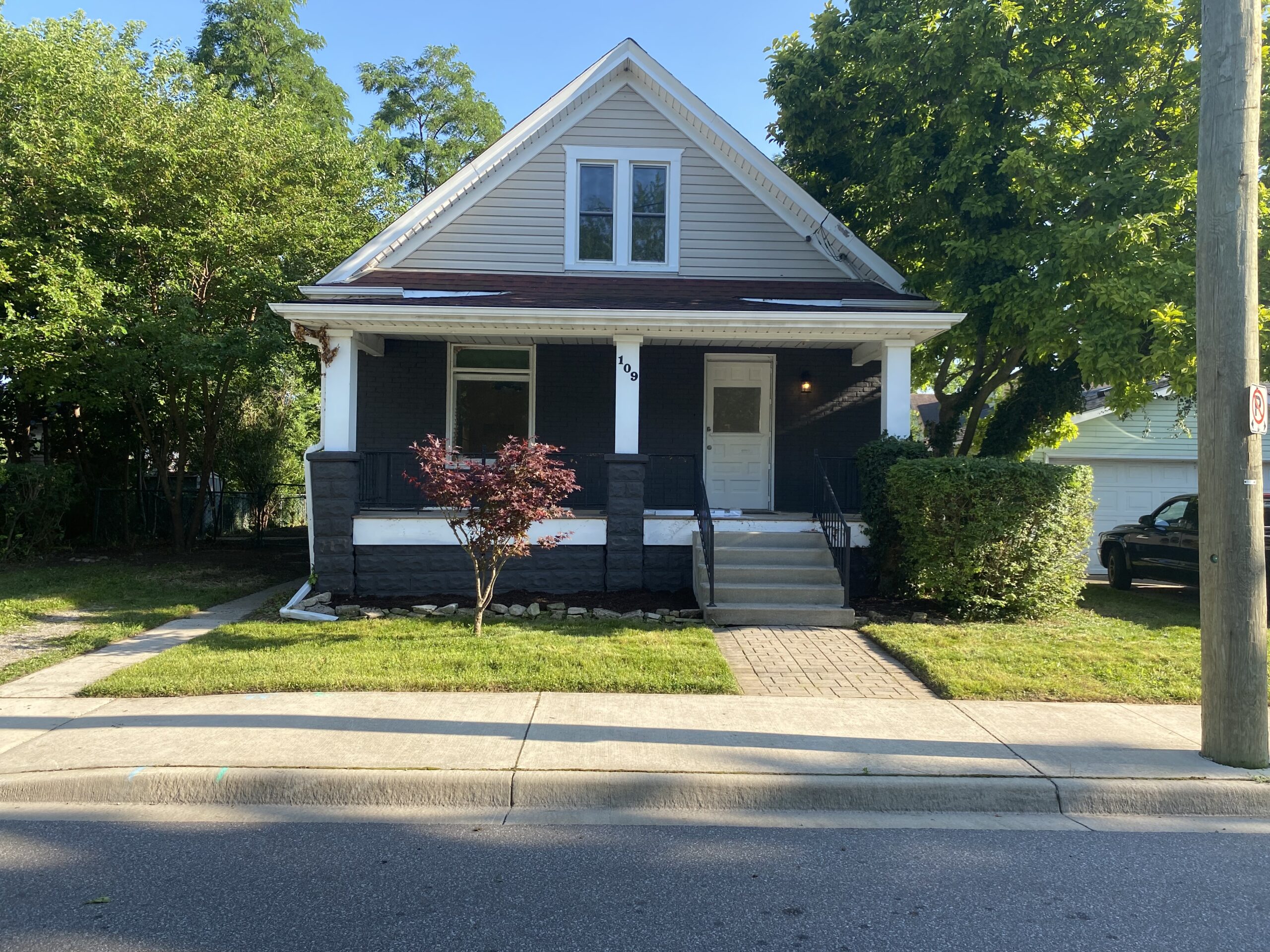 Front view of a well-maintained house showcasing professional landscaping services, featuring a manicured lawn, decorative shrubs, and a welcoming porch area.